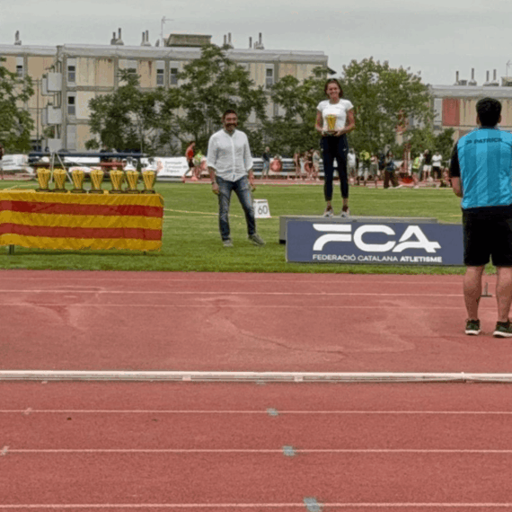 Una atleta al podi acaba de rebre el trofeu de mans del director general de Mutuacat, Sergi Macià, durant la 28a edició del Mítilng Internacional d'Atletisme Ciutat de Barcelona