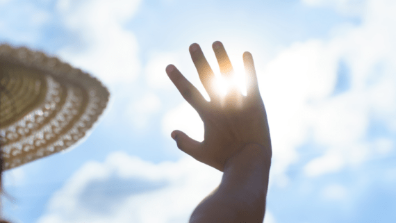 Una persona es protegeix del sol amb la mà i un nbarret, durant una onada de calor