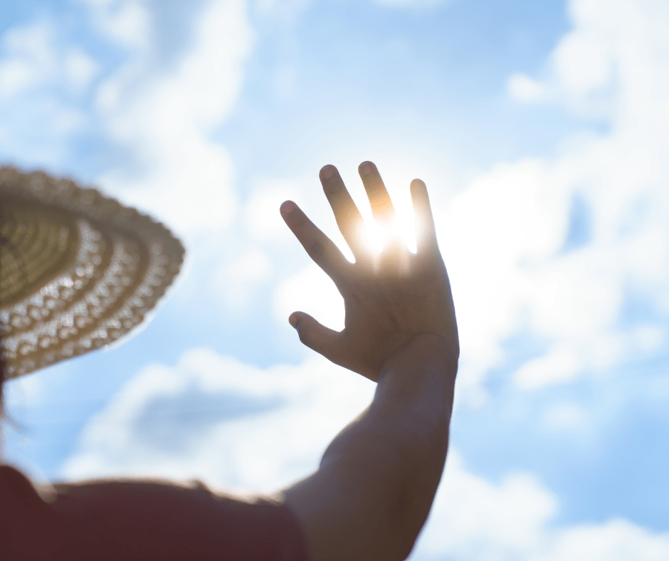 Una persona es protegeix del sol amb la mà i un nbarret, durant una onada de calor