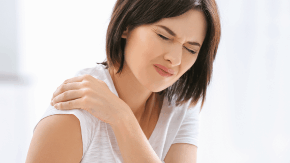 Una noia amb la mà a l'espatlla i amb cara de dolor. Probablementt pateix sinovitis