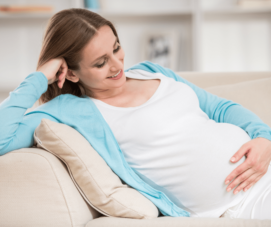 Dona embarassada, que somriu mirant la panxa, en una etapa on és essencial conèixer el calendari d’embaràs