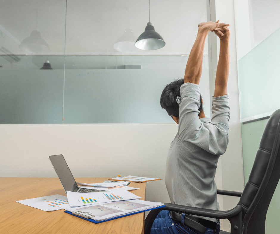 Una persona fa estiraments a la taula de treball. Per prevenir el mal d'esquena és recomanable fer pauses breus per moure's.