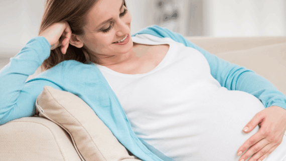 Dona embarassada, que somriu mirant la panxa, en una etapa on és essencial conèixer el calendari d’embaràs